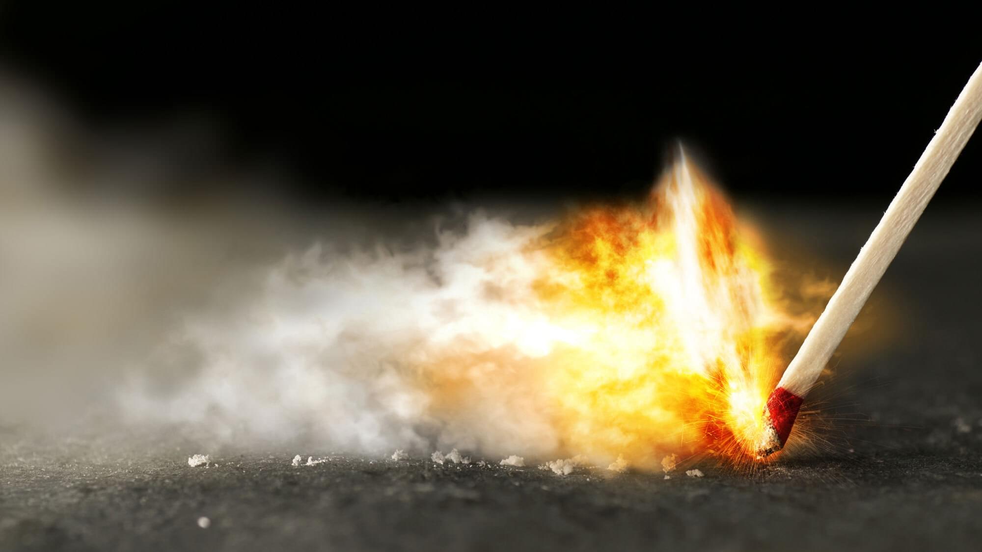 High resolution macro shot of a wooden kitchen match striking on a grey slate surface.